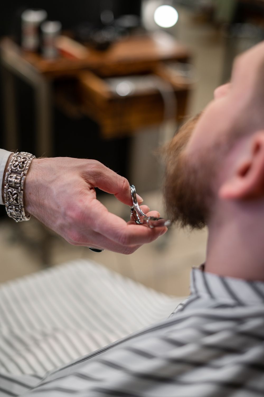 A barber trimming a beard with scissors